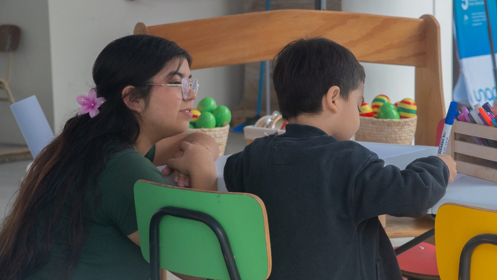 Estudiante de la UNAP acompañando a un niño en una actividad de aprendizaje